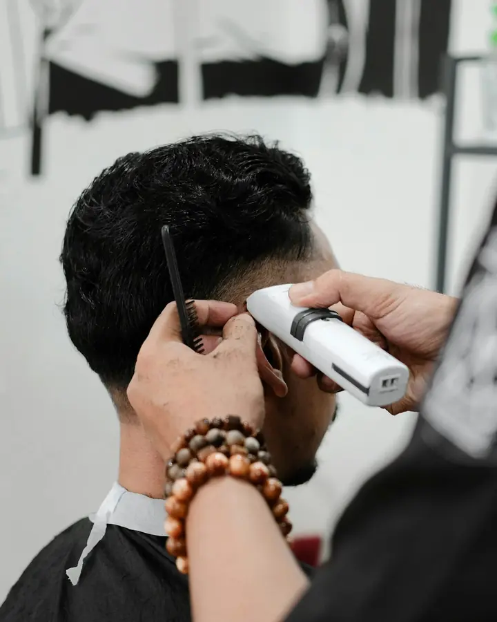 Barber merapikan potongan rambut dengan clipper
