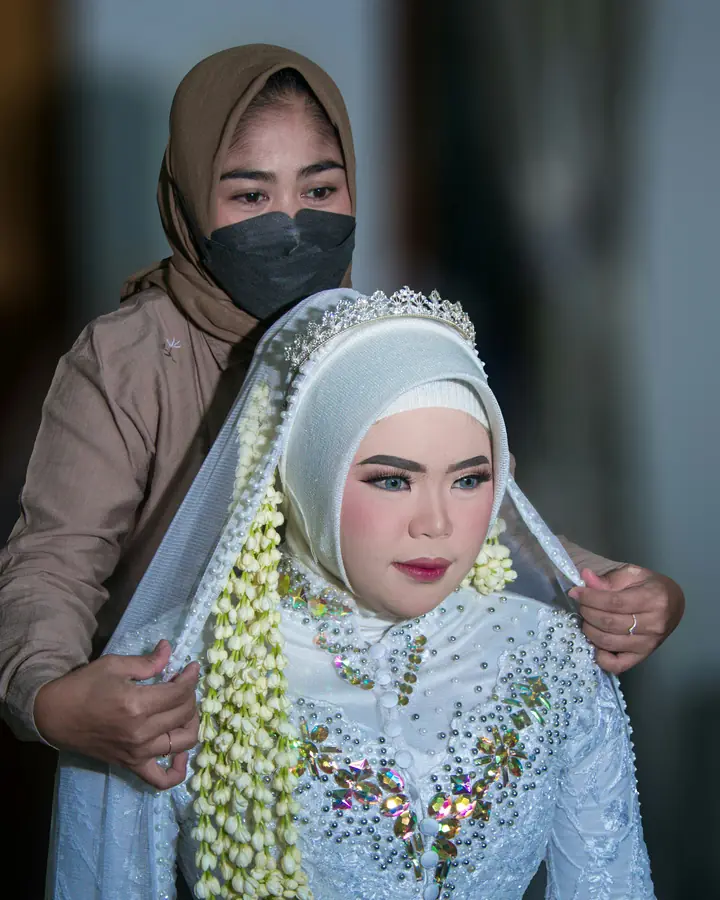 Make-up artist merapikan kerudung pengantin sebelum akad