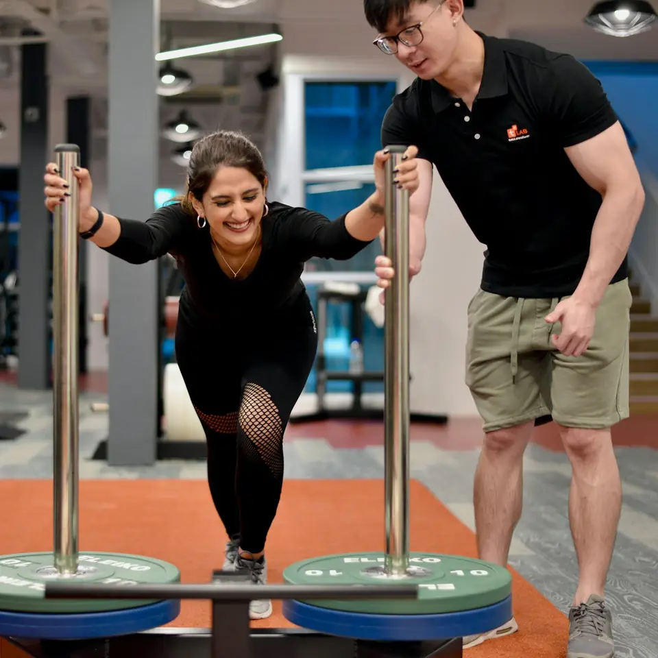 Personal trainer mendampingi kliennya latihan di gym