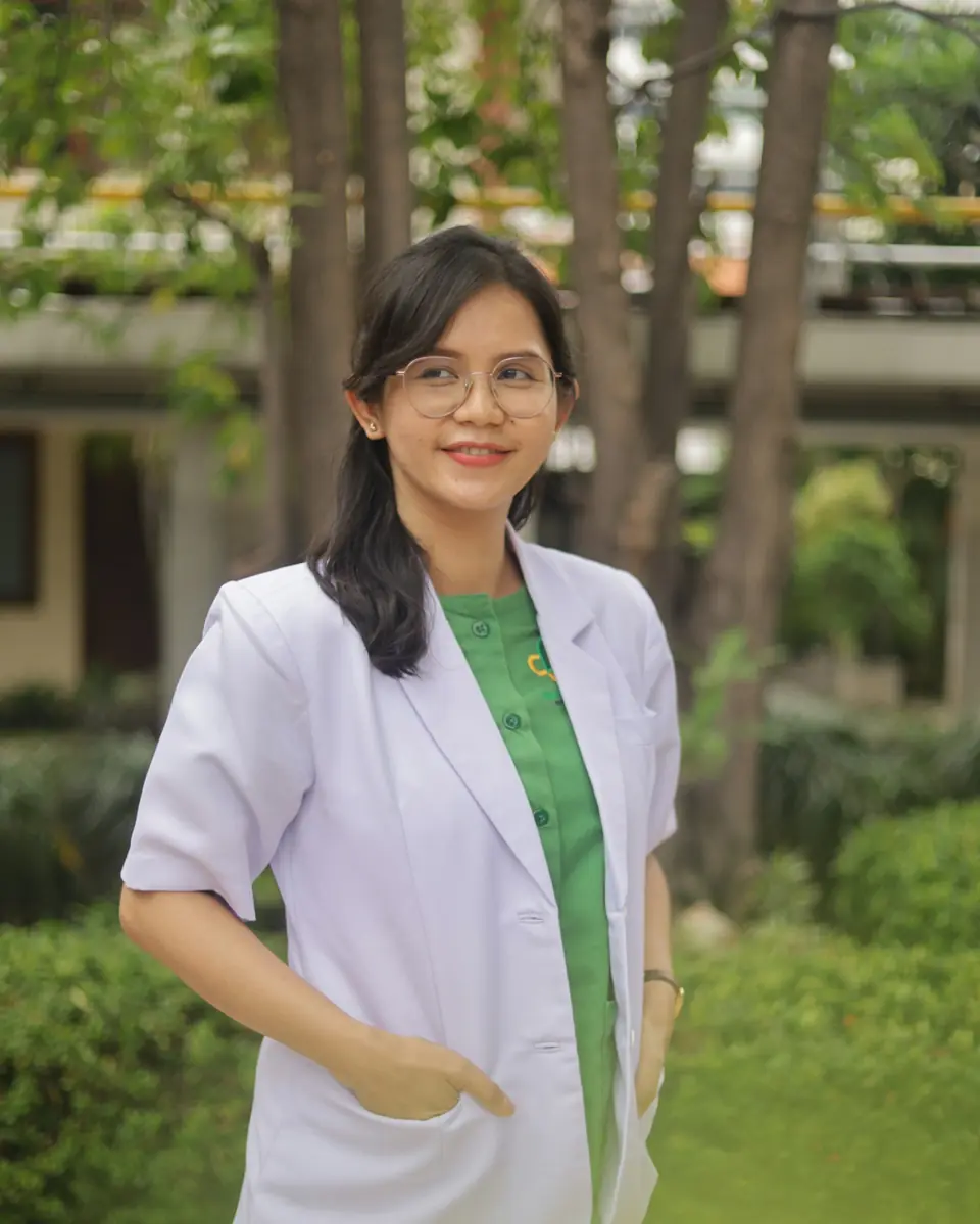 Dokter berjas putih tersenyum di taman klinik