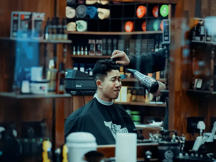 Barber mengeringkan rambut pelanggan di barbershop