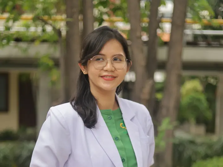 Dokter berjas putih tersenyum di taman klinik